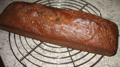 Ein saftiger Rührkuchen kühlt auf einem runden Metallgitter ab, umgeben von einer grauen Küchenarbeitsplatte.