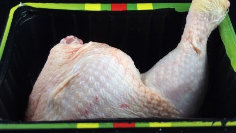 Im Behälter liegt ein gefrorenes Hähnchenbein, das darauf wartet, aufgetaut zu werden. Der Behälter hat eine bunte Umrandung.