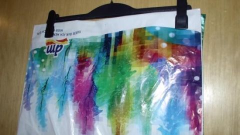 Mehrere bunte Plastiktüten hängen an einem Kleiderbügel, ordentlich aufbewahrt in einer hellen Küchennische.