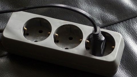 Um Strom zu sparen, sollte man alle Geräte die STANDBY laufen komplett ausschalten (also Stecker raus aus der Dose). Auch wenn kein Licht brennt, Stecker raus aus der Dose. Eine mehrfach Steckdose liegt auf einem dunklen Untergrund und hat ein Kabel angeschlossen, um Strom zu sparen.