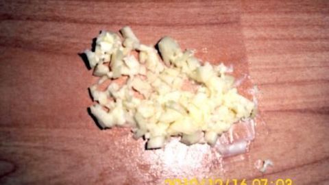 Knoblauchwürfel springen beim Schneiden nicht weg Klein geschnittene Knoblauchwürfel liegen auf einem Holzbrett und warten darauf, verwendet zu werden, ohne wegzuspringen.