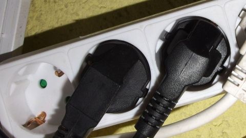Ein Stromanschluss mit mehreren Steckdosen und zwei schwarzen Steckern, möglicherweise für ein defektes elektrisches Gerät.
