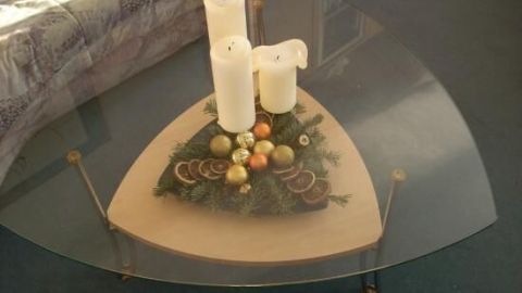 Auf einem Tisch steht eine Adventsdeko mit Kerzen und bunten Kugeln, umgeben von einer gemütlichen Wohnzimmeratmosphäre.
