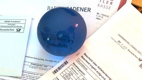 Ein runder blauer Stift liegt auf einem Stapel mit diversen Postdokumenten, um Ordnung in die alltägliche Post zu bringen.