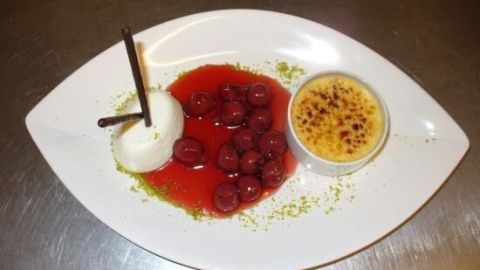 Ein dezentes Dessert zeichnet sich durch eine Limonen-Quarkmousse, Amarettokirschen in roter Sauce und eine Crème brûlée aus.
