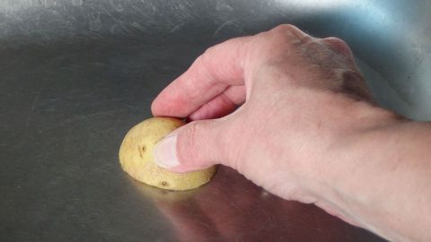 Eine Hand reinigt mit einer halben Zitrone eine Edelstahlspüle, um frischen Glanz zu erzielen.