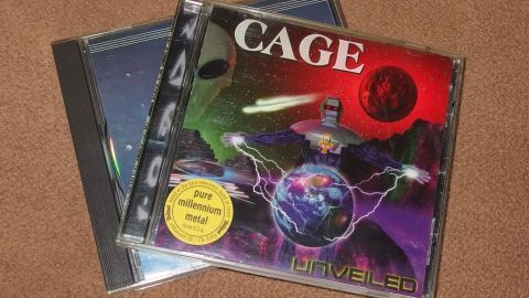 Ein CD-Case mit dem Titel "CAGE" liegt auf einem Tisch neben einem anderen CD-Case, ideal für den Austausch von Musik-CDs.