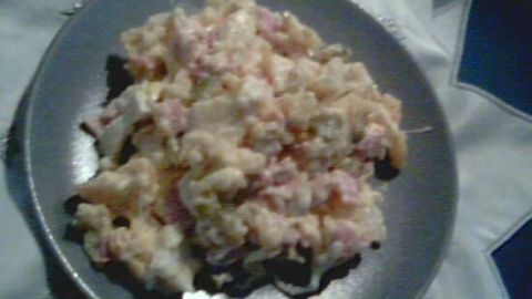 Ein Teller mit cremigem Sechs-Salat, gefüllt mit Fleischstücken, ruht auf einem weißen Tuch, bereit zum Servieren.