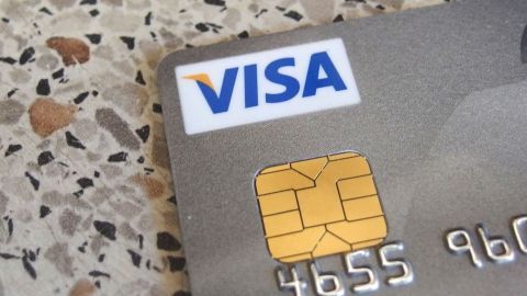 Eine Kreditkarte liegt auf einem gestreuten Tisch. Die Karte zeigt das Visa-Logo und eine Kontaktchip.