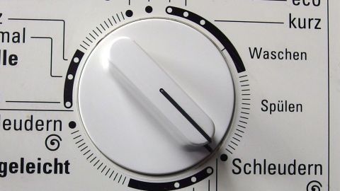 Ein Wäschetrockner zeigt das Einstellrad für verschiedene Programme. Der Nutzer wählt die Funktion „Schleudern“ in der Küche.