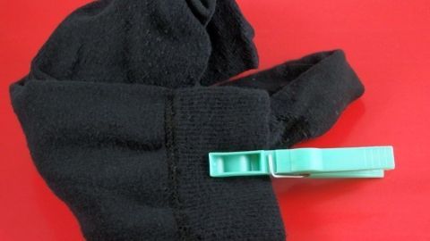 Ein schwarzer Socken wird mit einer grünen Klammer fixiert, um das Sortieren von Socken zu erleichtern.