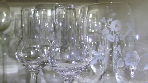 Elegante Gläser stehen in einer Vitrine und reflektieren das Licht, bereit zum Spülen und Wiedereinräumen.