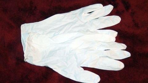 Ein paar weiße Gummihandschuhe liegen auf einem roten Tuch, bereit zur Verwendung bei der Stuhlgang Inkontinenzbehandlung.