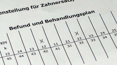 Ein Dokument mit einem Befund und Behandlungsplan für Zahnersatz zeigt Tabellen und Zahlen für die Planung.