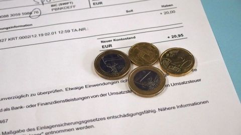 Mehrere Münzen liegen auf einem Dokument. Es könnte um einen Spartipp für Menschen mit kleinem Budget gehen.