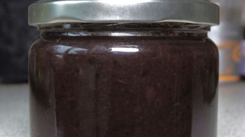 Ein Einmachglas mit dunkler Marmelade steht auf einer Arbeitsfläche, bereit zum Einfrieren der Gerichte.