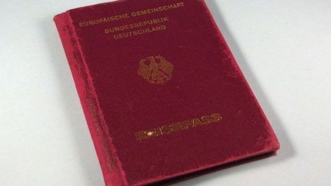 Wichtige Reisedokumente (Pass, Visum, Versicherung, etc.) sollte man zur Sicherheit scannen oder fotografieren und an die eigene E-Mail-Adresse mailen. Ein rotes Passbuch liegt auf einer neutralen Oberfläche, bereit zum Scannen oder Fotografieren für wichtige Reisedokumente.