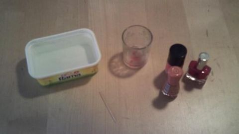 Eine Teelicht-Gläser-Deko wird mit einem leeren Behälter, einem Glas und Nagellacken auf einem Tisch arrangiert.