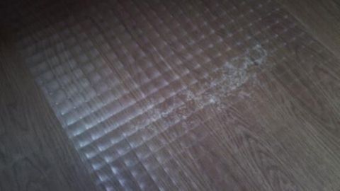 Ein glänzender Laminatboden zeigt, dass er Schutz benötigt, während eine verschmutzte Stelle sichtbar ist.