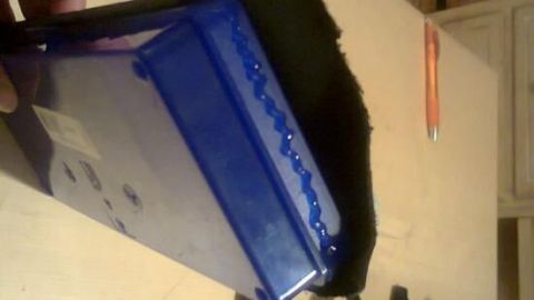 Ein blauer Schmuckkästchen wird gehalten, während es geöffnet wird, um Ohrstecker auf einem Tisch zu zeigen.