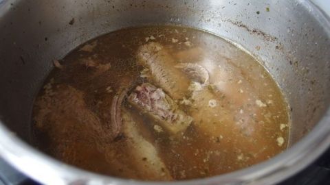 Eine silberne Kochtopf enthält eine köstliche Fleischbrühe, die köchelt und würzige Aromen entfaltet.