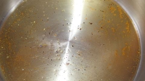 Ein Topf mit heißem Öl, das vielschichtig braun schimmert, bereit zum Braten von Hackfleisch.