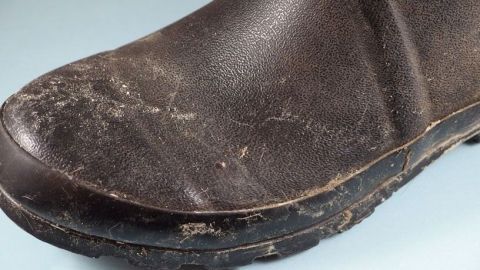 Schmutzige, eingematschte Schuhe liegen auf einem hellblauen Hintergrund und zeigen starke Verunreinigungen und Abnutzungsspuren.