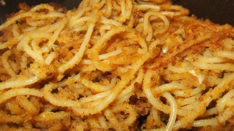 Knusprige, gebackene Spaghetti in Nahaufnahme, mit goldbrauner Kruste, in einer Pfanne zubereitet.