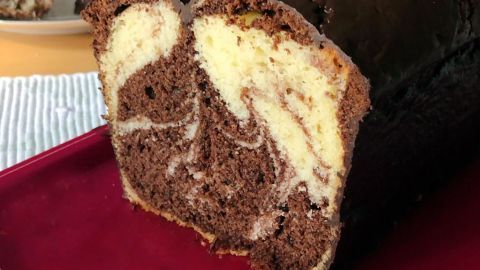 Saftiger Marmorkuchen liegt auf einem roten Teller, mit einem köstlichen Marmorierungsmuster aus Schokolade und Vanille.