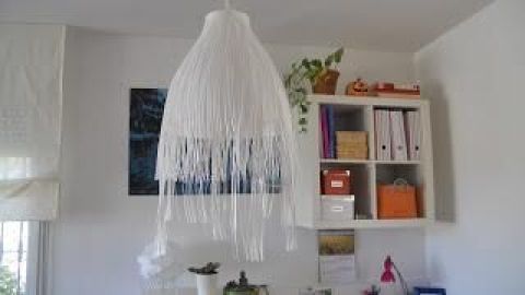 Eine elegante IKEA-Lampe hängt von der Decke und strahlt sanftes Licht in einem modernen Raum mit hellen Möbeln.
