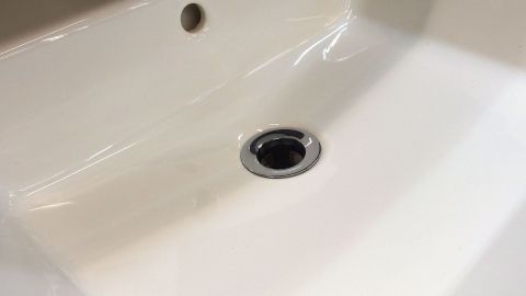 Ein glänzendes Waschbecken zeigt den Abfluss, der bereit ist, Wasser frei abfließen zu lassen in einem modernen Bad.