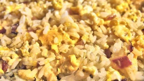 Gebratener Reis mit Eiern und Stückchen, goldbraun gebraten, präsentiert in einem bunten, gemütlichen Küchenumfeld.