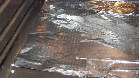 Um Verschmutzungen im Backofen vorzubeugen, lege ich Alufolie am Boden des Backofens aus und kann dann die Alufolie entsorgen. Ein Backofen ist mit Alufolie ausgelegt, die glänzend auf dem Rost liegt, um ihn sauber zu halten.