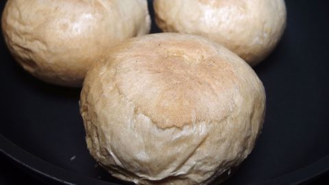 Drei tiefgekühlte Brötchen liegen in einer Pfanne und werden gerade aufgetaut und aufgebacken, ohne Backrohr.