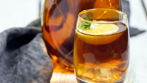 Ein Glas Southern Comfort mit Sprite steht neben einer dekorativen Flasche auf einem rustikalen Holztisch und schwarzen Tüchern.