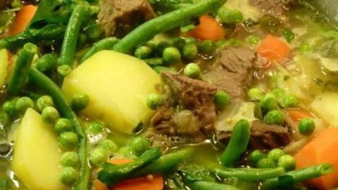 Ein Rindfleisch-Gemüsetopf mit zartem Fleisch, Kartoffeln und buntem Gemüse in einer großen Pfanne, köchelnd.