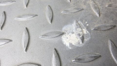 Eine graue, rutschfeste Oberfläche mit Vogeldreck in der Mitte. Der Schmutz hebt sich visuell von der strukturierenden Matte ab.
