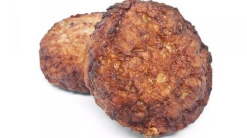 Zwei gebratene Fleischküchle aus Gemüse ruhen auf weißem Hintergrund, knusprig und appetitlich.