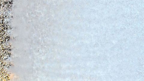 Eisige Autoscheiben sind sichtbar, während das Innere eines Fahrzeugs erkennbar ist; kalte Temperaturen verursachen Vereisung.