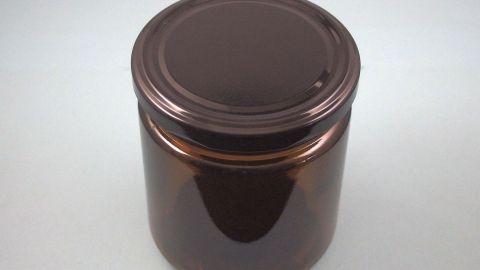 Ein dunkelbraunes Glas steht auf einem weißen Tisch, bereit zur Weiterverwendung für Brühe oder andere Lebensmittel.