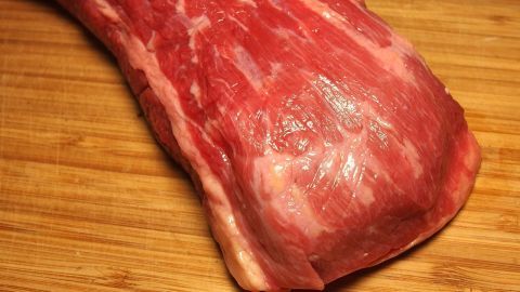 Ein frisches Stück Fleisch liegt auf einem Holztisch, bereit für die Zubereitung in einem türkischen Laden.