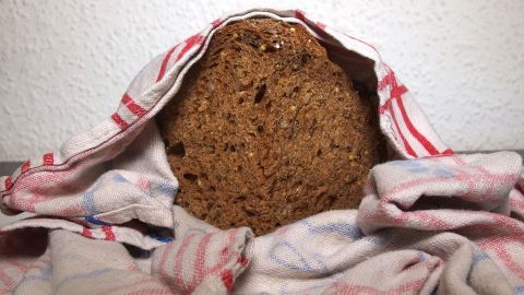 Ein gefrorenes Brot liegt unter einem Küchenhandtuch und taut auf, bereit zum Verzehr in einer häuslichen Umgebung.