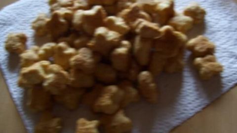 Hundeleckerlis liegen auf einem weißen Tuch. Sie sind frisch gebacken und in verschiedenen Formen auf einem Holztisch verteilt.