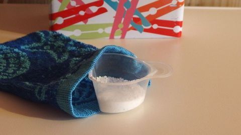 Weißes Waschpulver liegt in einem Messbecher auf einem Handtuch, bereit zum direkten Einfüllen in die Trommel.