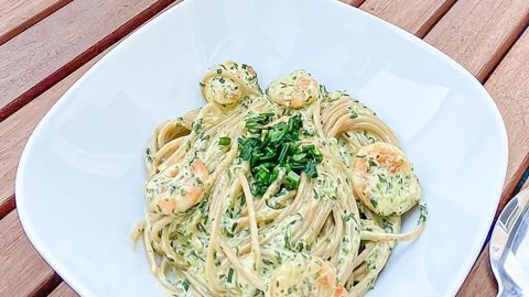 Spaghetti mit Tiefseegarnelen werden in einer weißen Schüssel serviert und mit frischem Schnittlauch garniert.