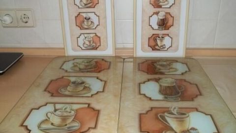Vier dekorative Untersetzer mit Kaffeetassen-Motiven liegen auf einer Küchenarbeitsfläche und verleihen der Küche Charme.