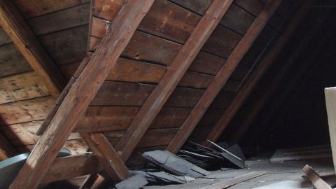 Marder auf dem Dachboden mit altem Parfüm vertreiben. Ein leerer Dachboden mit schrägen Holzbalken und einigen alten Materialien, ideal für Marder-Vertreibung.