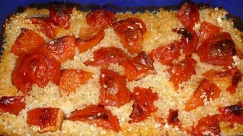 Gebackener Tomatenreis ist in einer blauen Auflaufform zu sehen, gebacken mit goldbraun ger&ouml;steten Tomaten obendrauf.