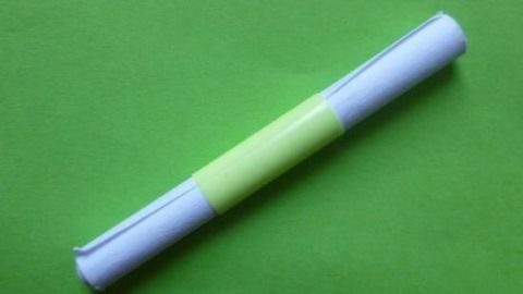 Tombolalose mit Trinkhalmstückchen zusammenhalten 1 Ein Rollenobjekt mit gelben und weißen Abschnitten liegt auf einem grünen Untergrund, bereit für eine Tombolalose-Verlosung.