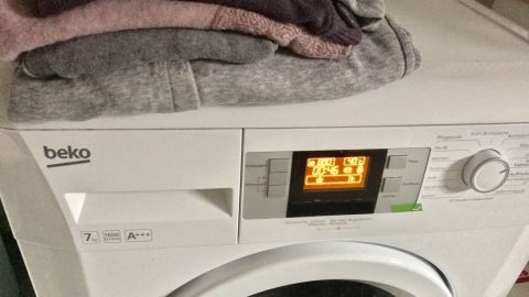 Auf einem weißen Wäschetrockner liegen ordentlich gefaltete, saubere Handtücher, die das Bügeln überflüssig machen.